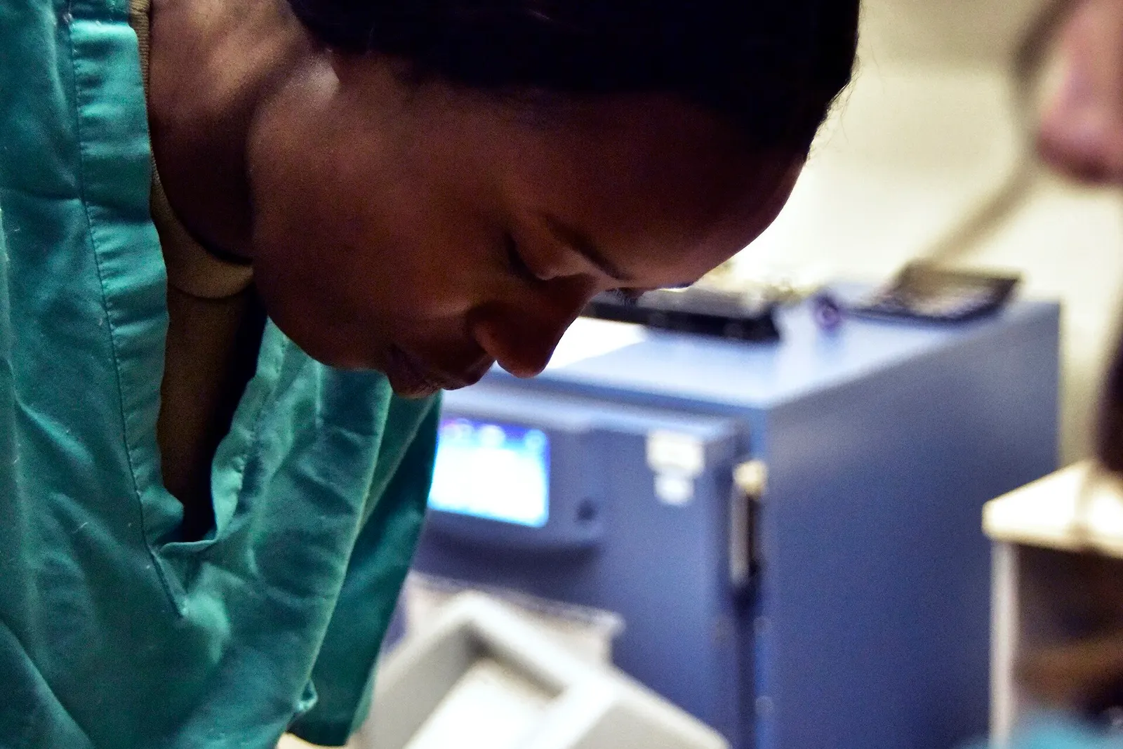 A technician in scrubs works at a clinic bench