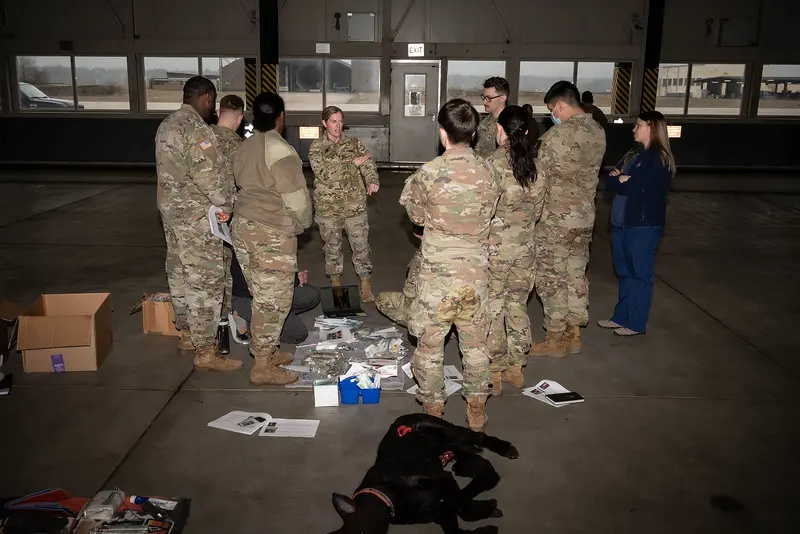 A group of animal care specialists gathered around a patient on the floor during a training session