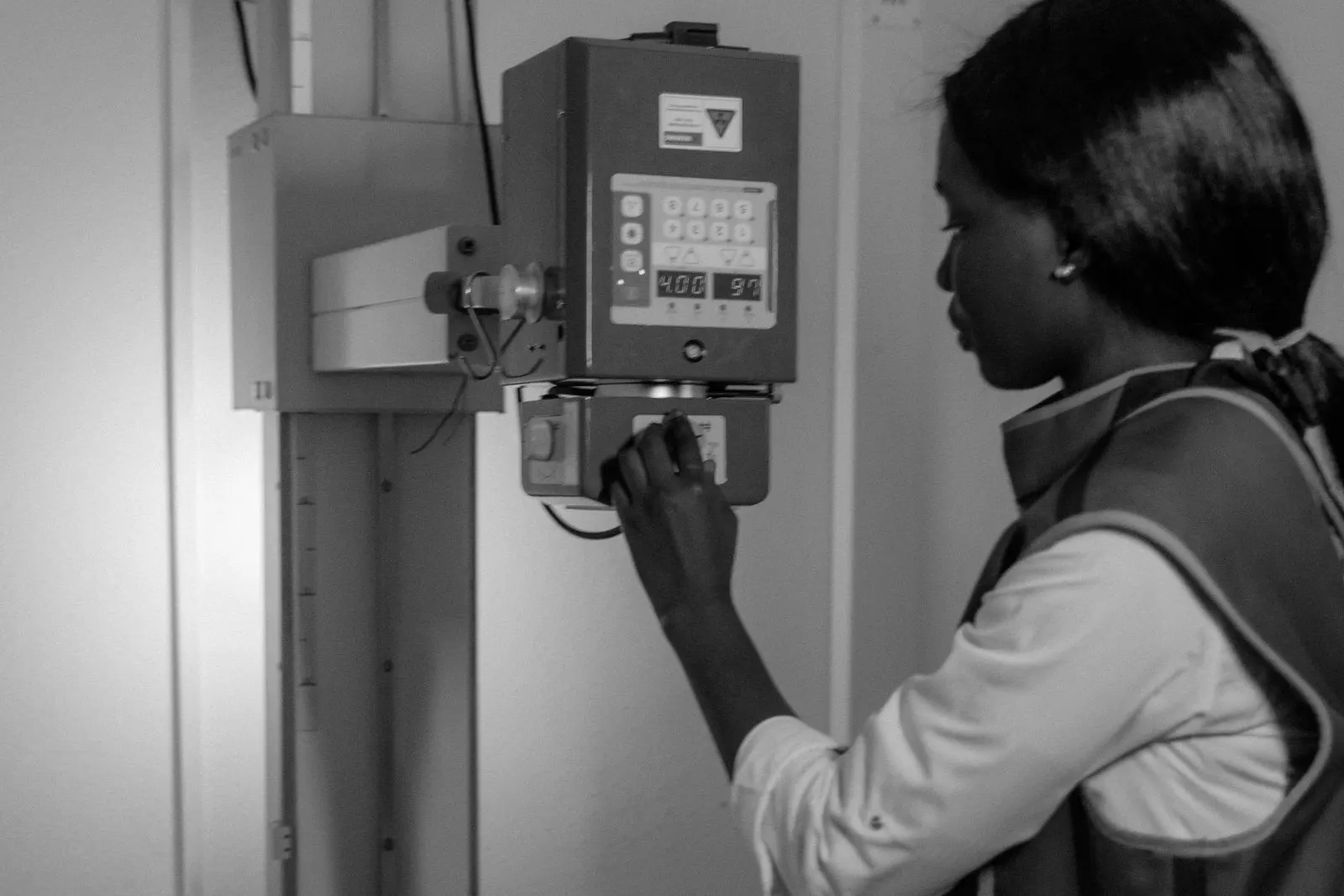 A technician in a lead apron positions a small dog on the x-ray table